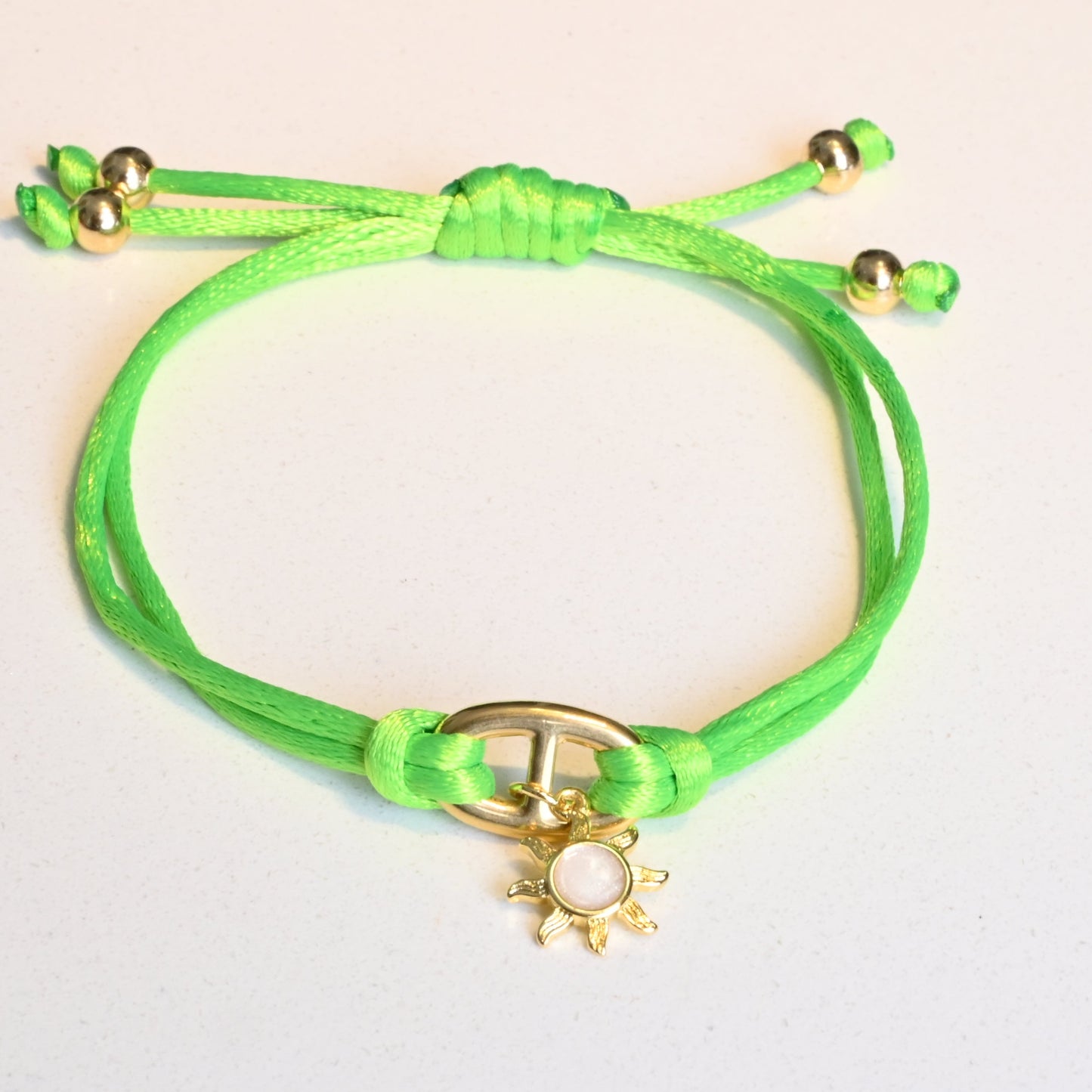Green bracelet with gold accents on a light gray background